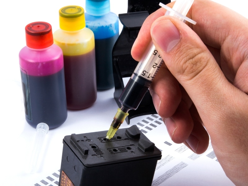 Refilling different types of ink cartridges using coloured ink bottles and syringe.